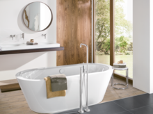 Bañera ovalada exenta de acero vitrificado, delante lavabo rectangular sobre encimera.